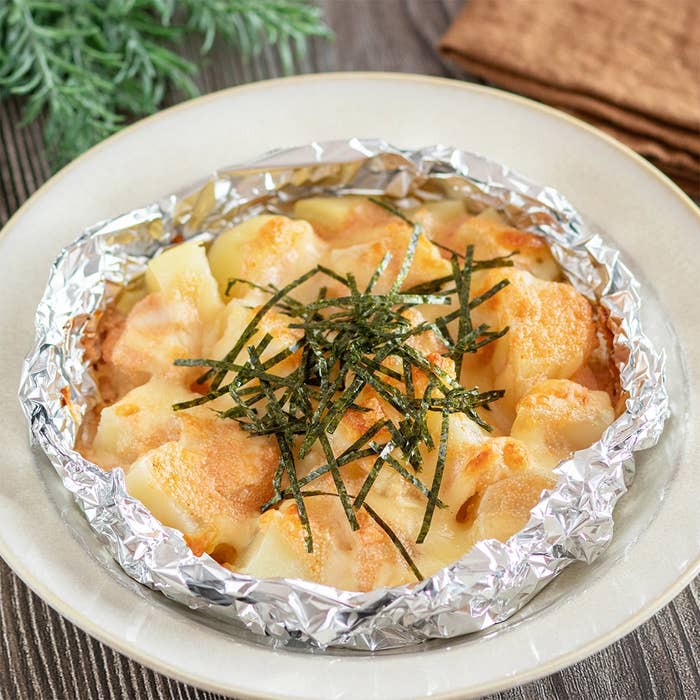 アルミホイルに包まれたポテトとチーズのグラチネ、上に刻み海苔がのせられている。