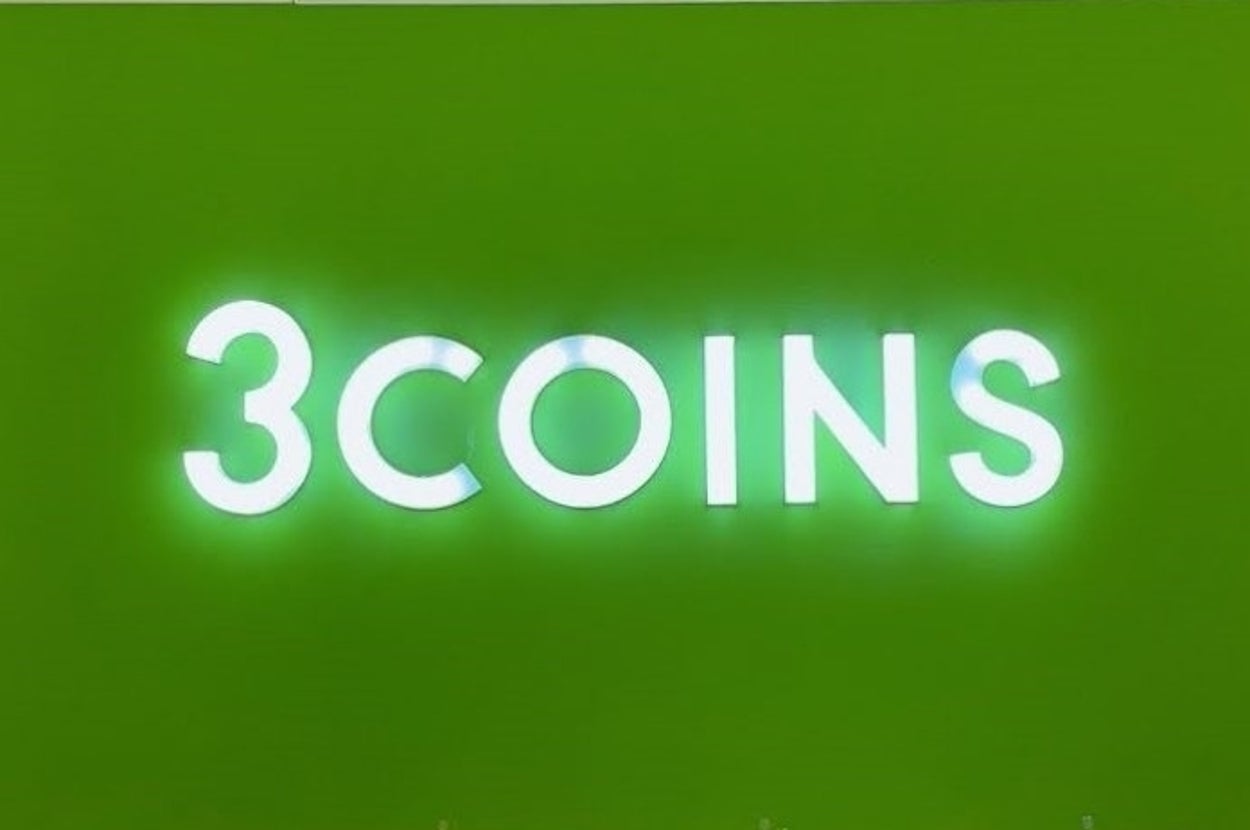 緑の背景に「3COINS」と光る看板がある。看板下に店内が少し見える。