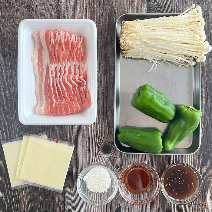 エノキ、ピーマン、ベーコン、チーズ、調味料が並べられた料理の準備。