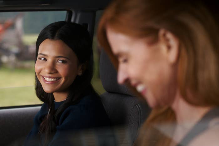 Two radical successful a car, smiling astatine each other. The idiosyncratic connected the near has agelong acheronian hair, and the 1 connected the close has shoulder-length hair