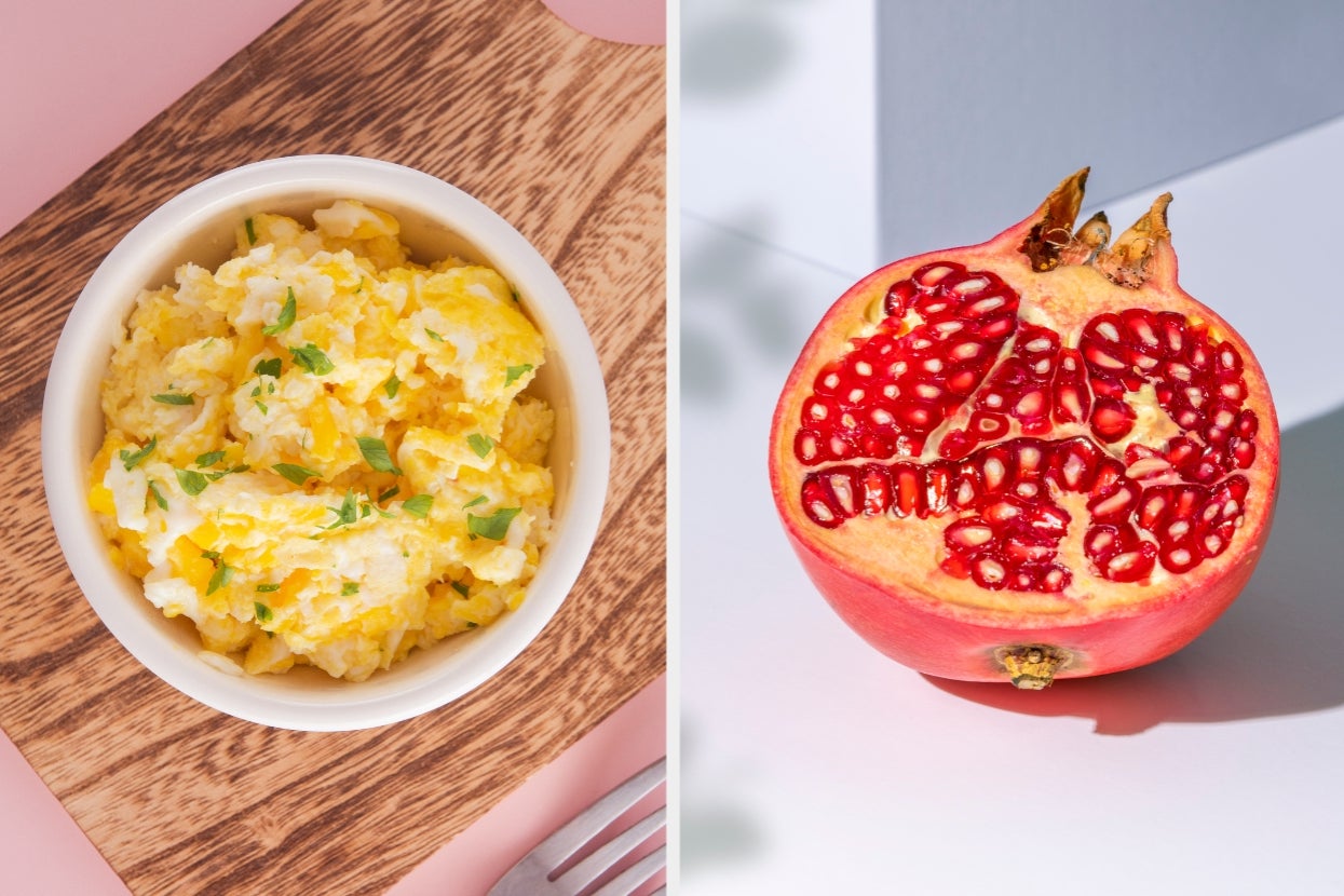 A bowl of scrambled eggs with herbs on a wooden board next to a sliced open pomegranate showing its seeds