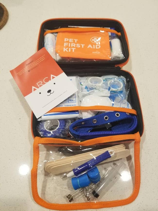 Open pet first aid kit containing bandages, wipes, and medical supplies, with an ARCA brochure visible