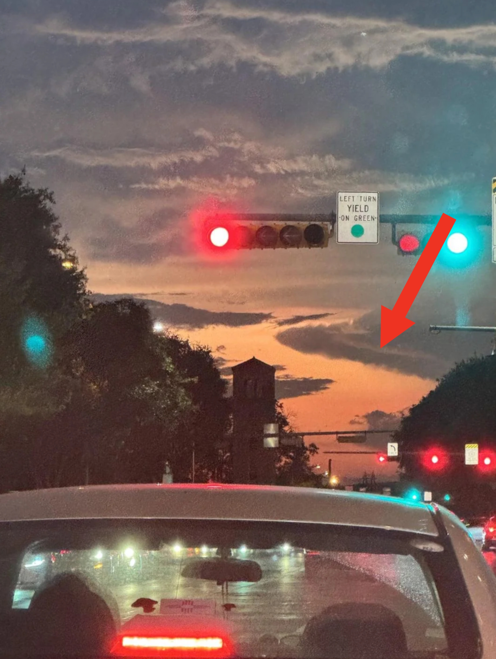 Traffic airy  astatine  intersection during sunset, presumption    from car   dashboard. Clouds and faint cityscape silhouette successful  the distance