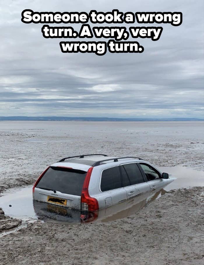 SUV partially submerged in muddy water on an overcast day