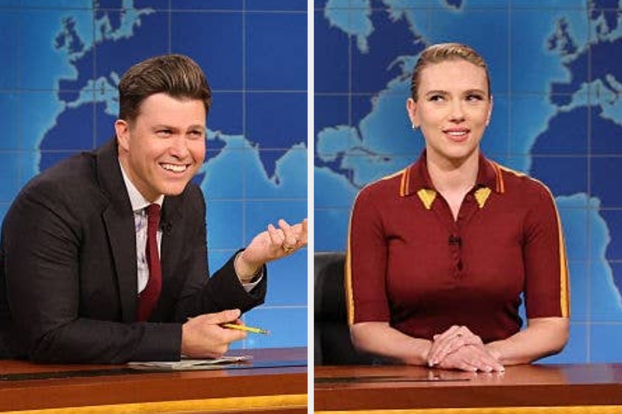 Two people sit behind a news desk on a set with a world map backdrop. The person on the left wears a suit; the other wears a casual top