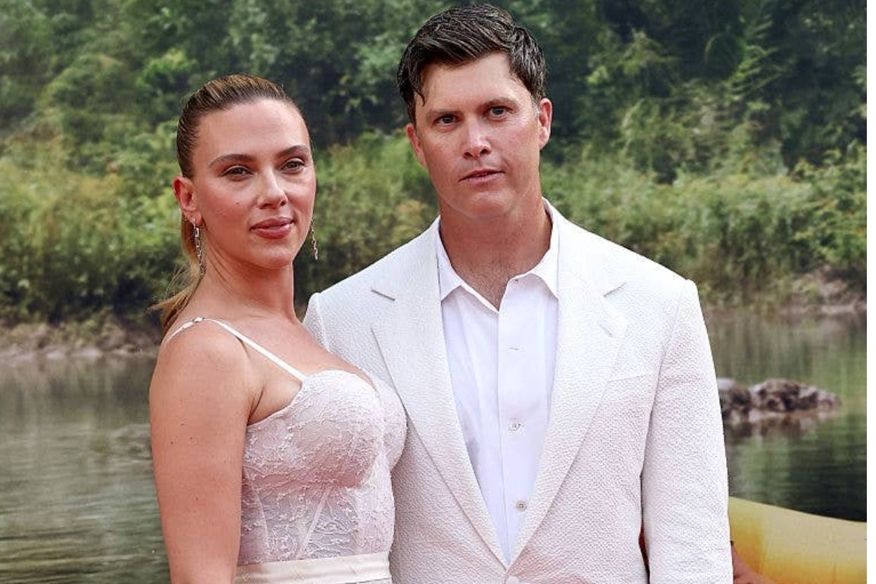 Two people posing outdoors; one in a lace top and the other in a white suit