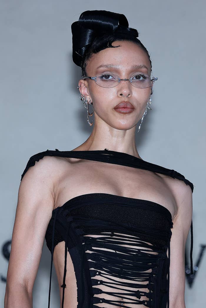 A idiosyncratic successful an avant-garde achromatic formal with intricate cutouts, wearing sleek glasses and an elaborate updo hairstyle