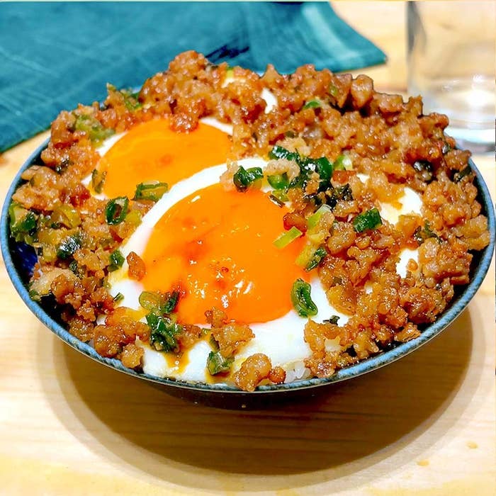 器に盛られたご飯の上に、半熟の卵と炒めた挽肉、ネギがのっている料理。