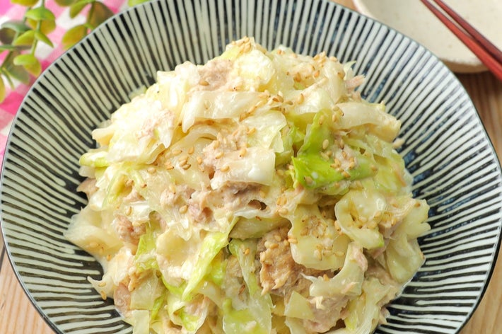 キャベツとツナのサラダが盛り付けられた大皿。皿の横には箸と植物が置かれている。