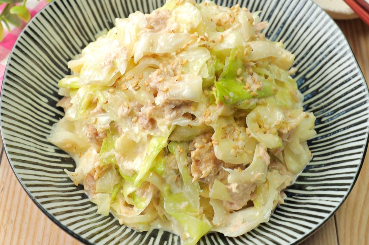 キャベツとツナのサラダが盛り付けられた大皿。皿の横には箸と植物が置かれている。