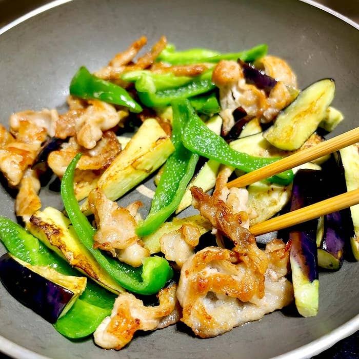 フライパンで調理中のピーマンとナス、肉の炒め物。