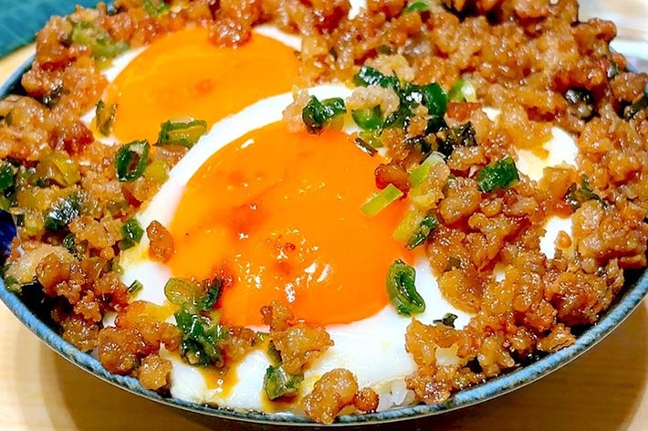 どんぶりの上に半熟卵と挽肉が盛られた料理。ボウルの上に美味しそうに配置されています。