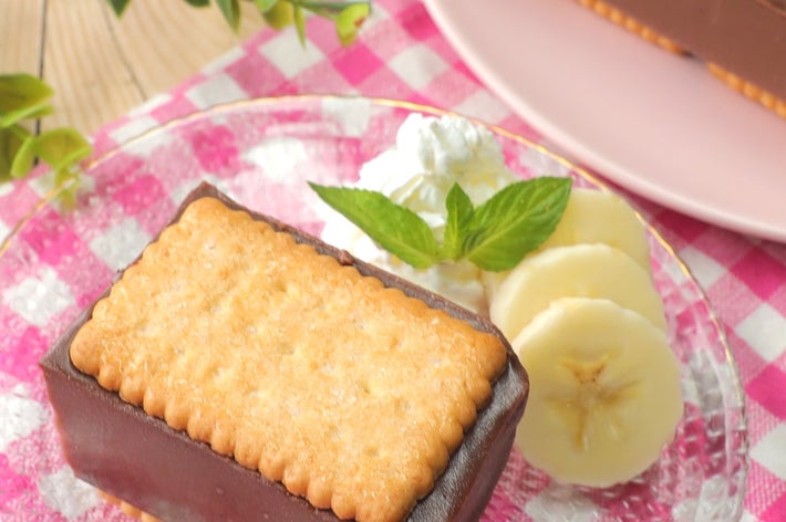 チョコレートケーキに挟まれたビスケットが乗ったデザート。バナナスライスとミントの葉が飾られている。
