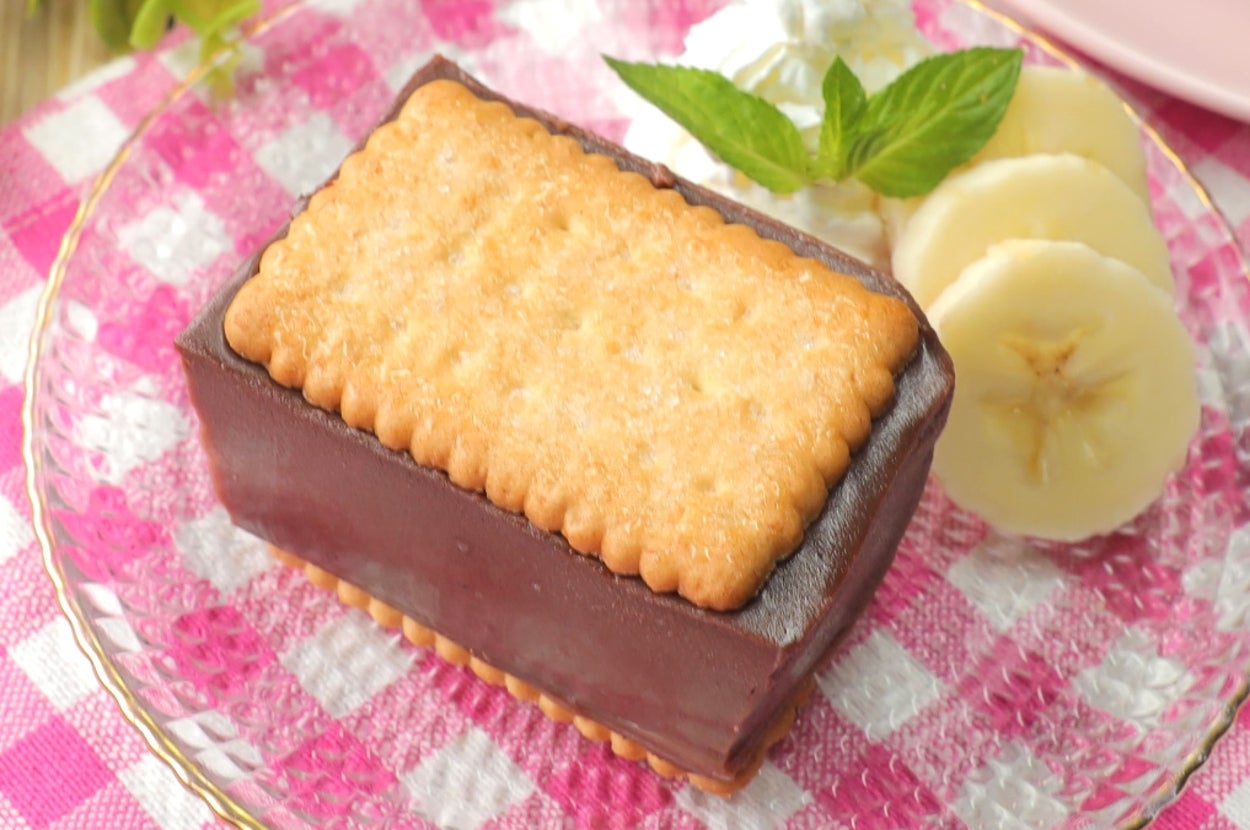 チョコレートケーキに挟まれたビスケットが乗ったデザート。バナナスライスとミントの葉が飾られている。
