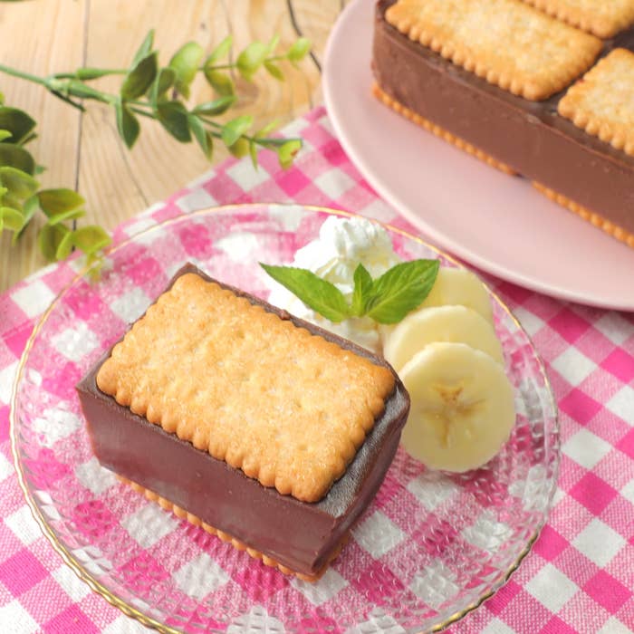 チョコレートケーキに挟まれたビスケットが乗ったデザート。バナナスライスとミントの葉が飾られている。