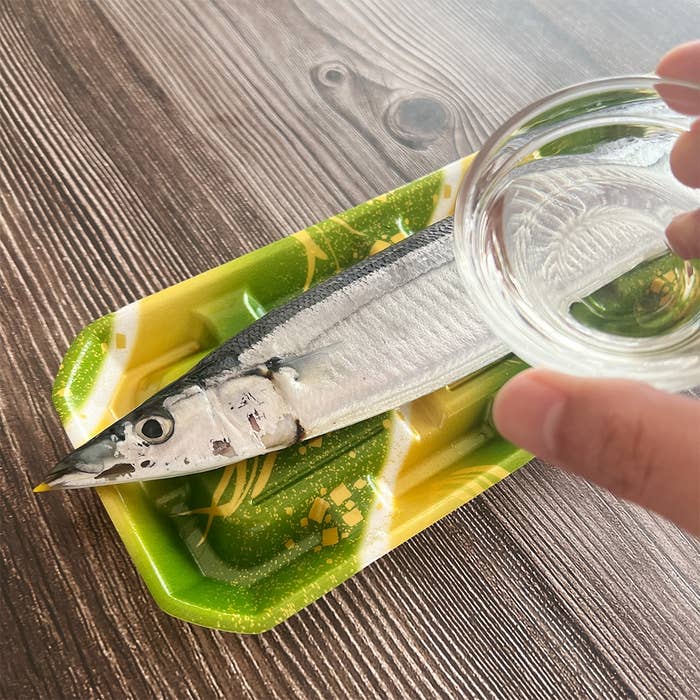 木製テーブルの上に置かれたサンマのパックに水を注ぐ様子。