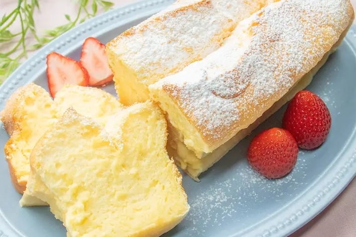 ふわふわのスフレケーキが青い皿に盛られており、横に苺と葉の装飾があります。