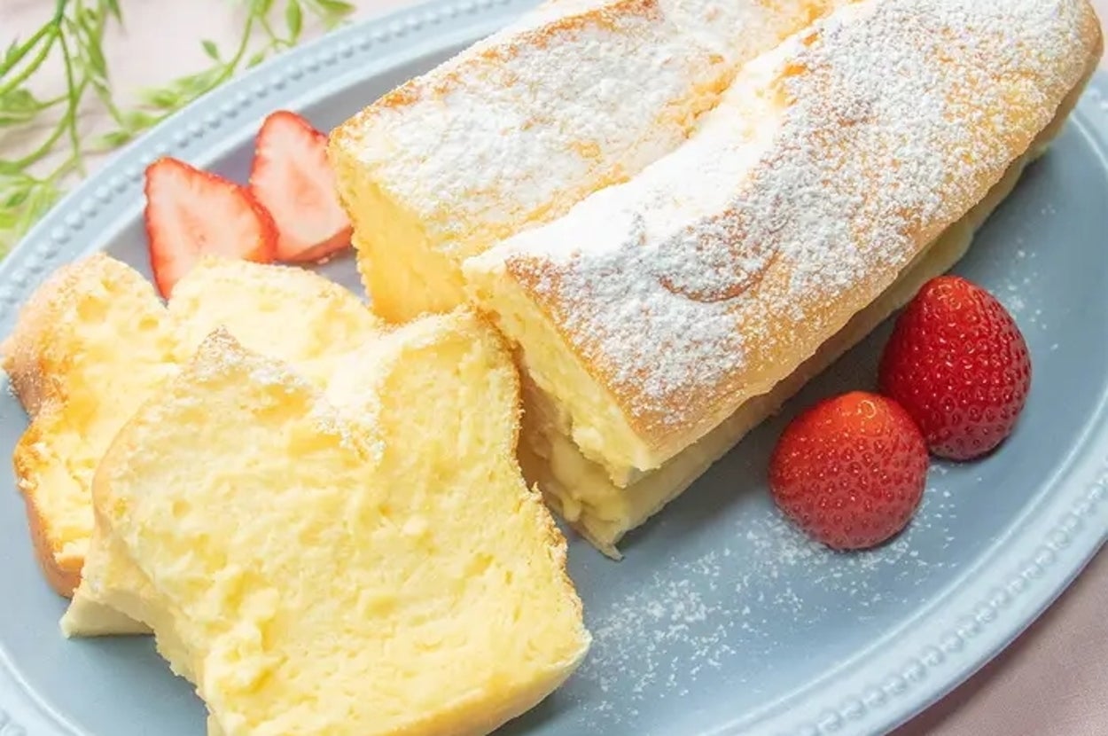 ふわふわのスフレケーキが青い皿に盛られており、横に苺と葉の装飾があります。