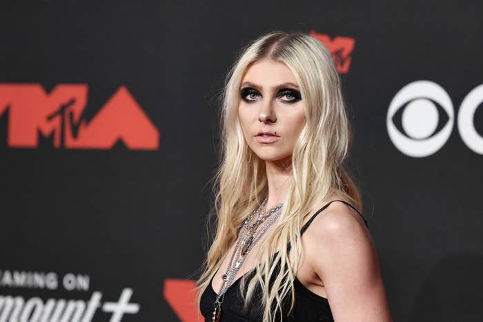 Person with agelong blond hairsbreadth wearing a stylish achromatic sleeveless outfit connected a reddish carpet astatine a personage event