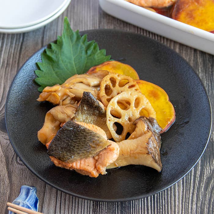 サケと野菜の料理が黒いプレートに盛られている。食卓に置かれている。