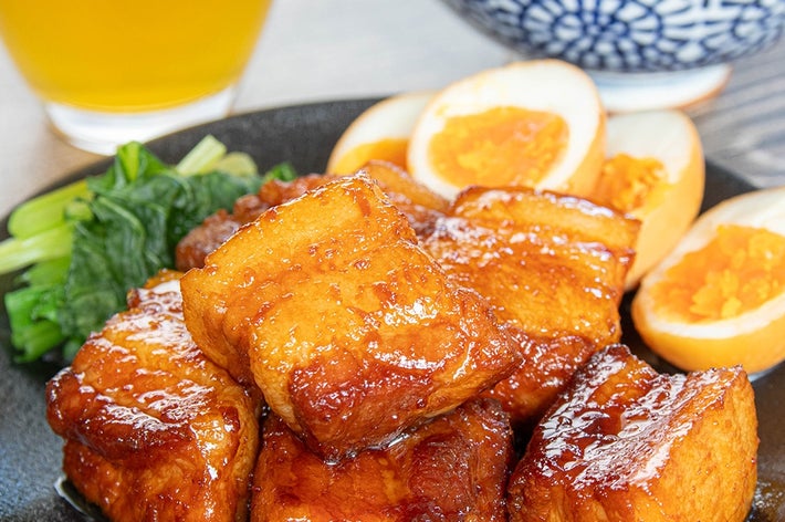 お皿に照り焼き豚の角煮、ゆで卵、ほうれん草。後ろにライスと飲み物。