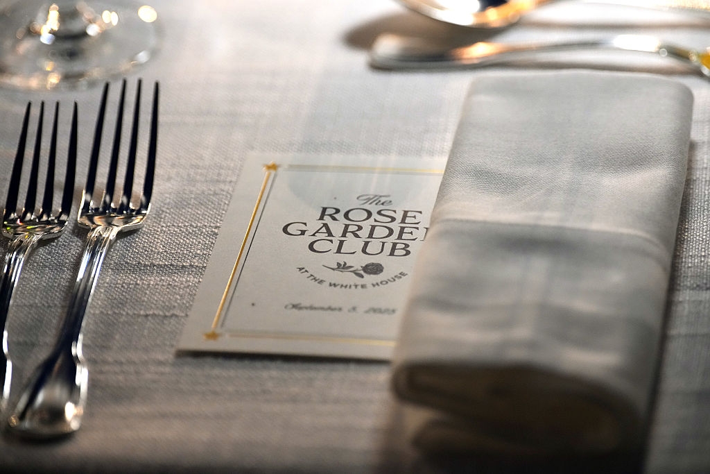 Place setting with two forks beside a folded napkin and a Rose Garden Club invitation card from the White House