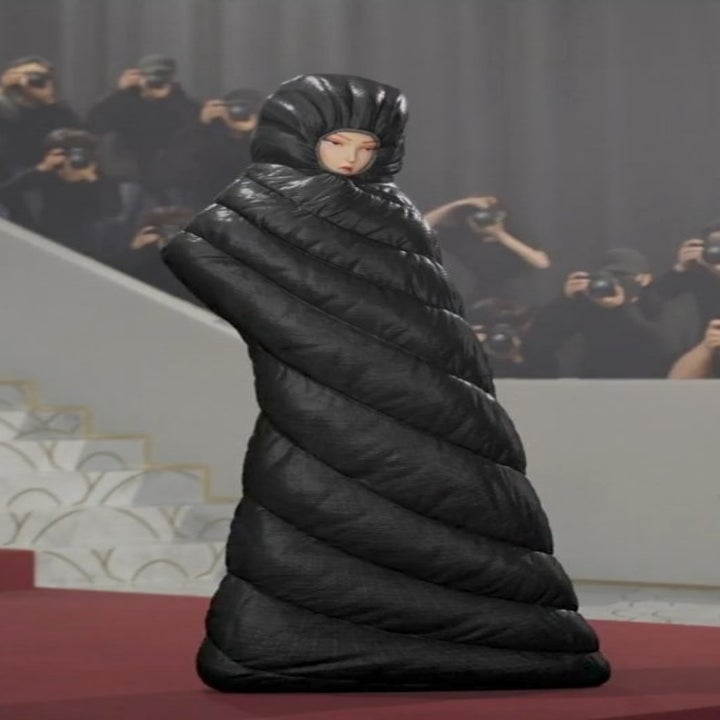 animated Mina on a red carpet in an avant-garde, cocoon-like quilted outfit, surrounded by photographers