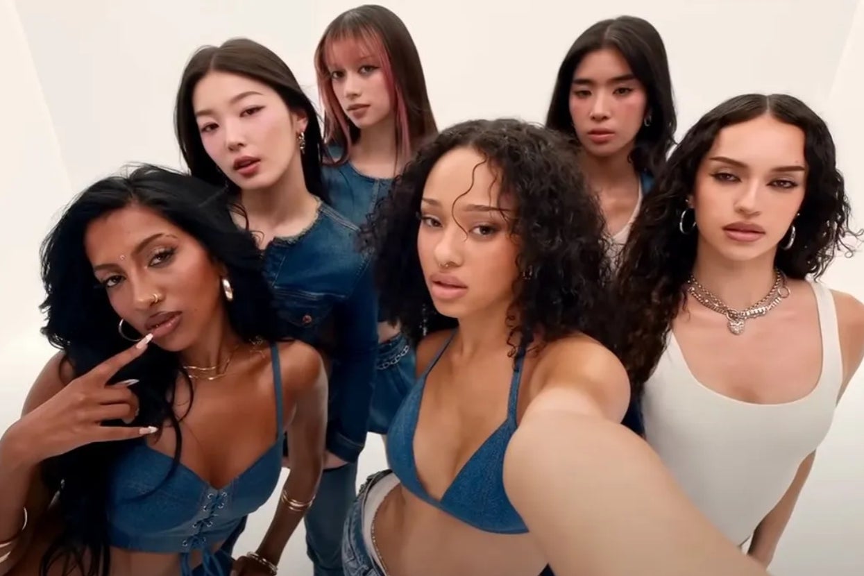 Six women pose confidently in casual denim and white tops, facing the camera with varied hairstyles and expressions