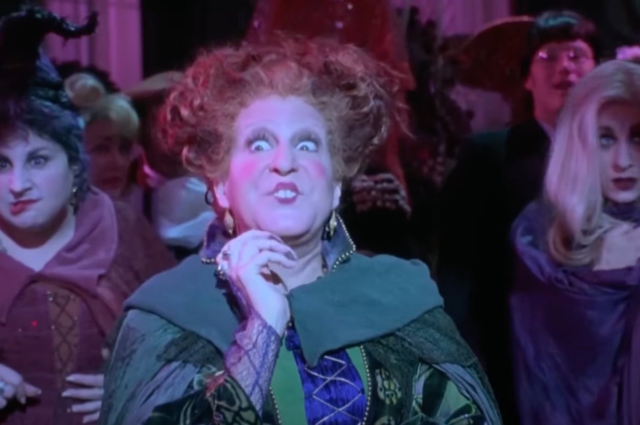 A character in a theatrical costume with elaborate hair and a dramatic expression is performing on stage