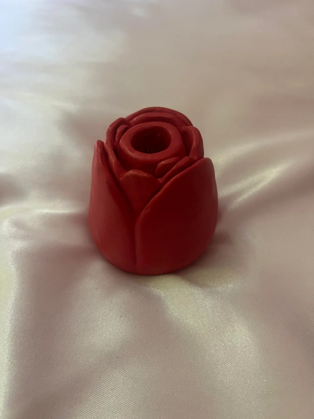 Rød voksskulptur formet som en rose på en glatt, lett overflate