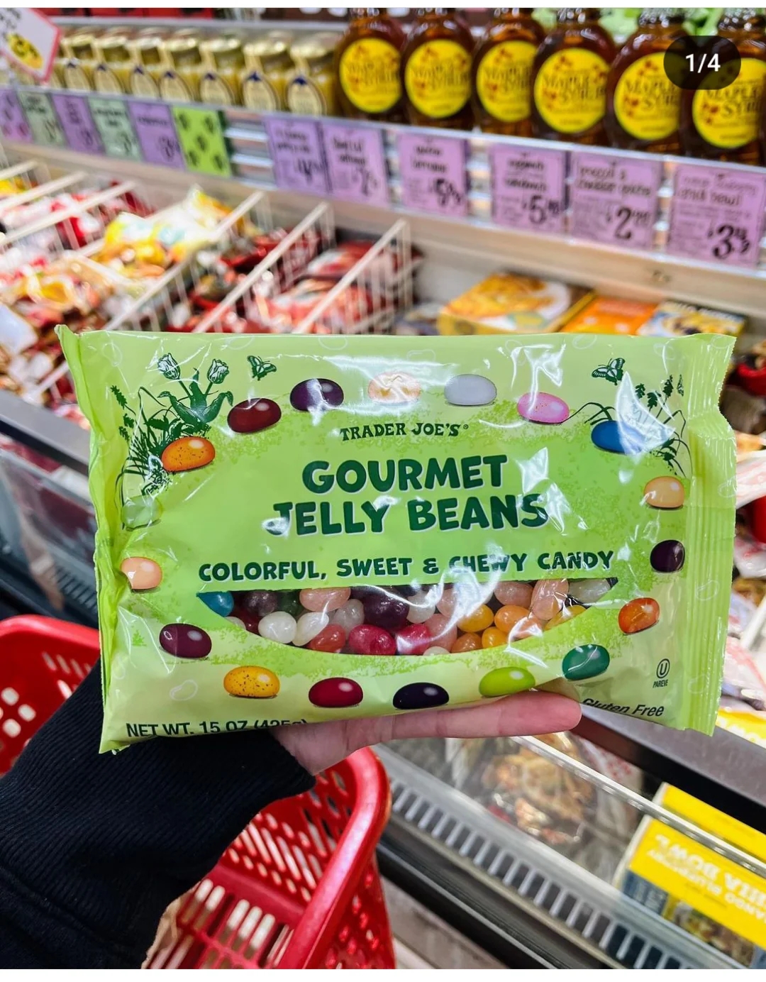 En hånd holder en pose med Trader Joe ' s gourmetlede bønner i en dagligvaregang, med forskjellige matvarer i bakgrunnen