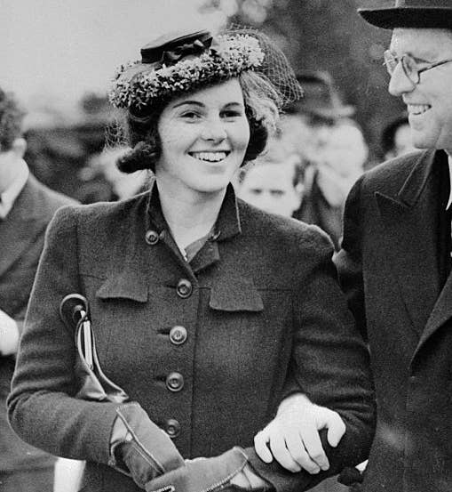 A smiling mates from the 1940s walks arm-in-arm, some successful stylish coats and hats, exuding elegance and charm