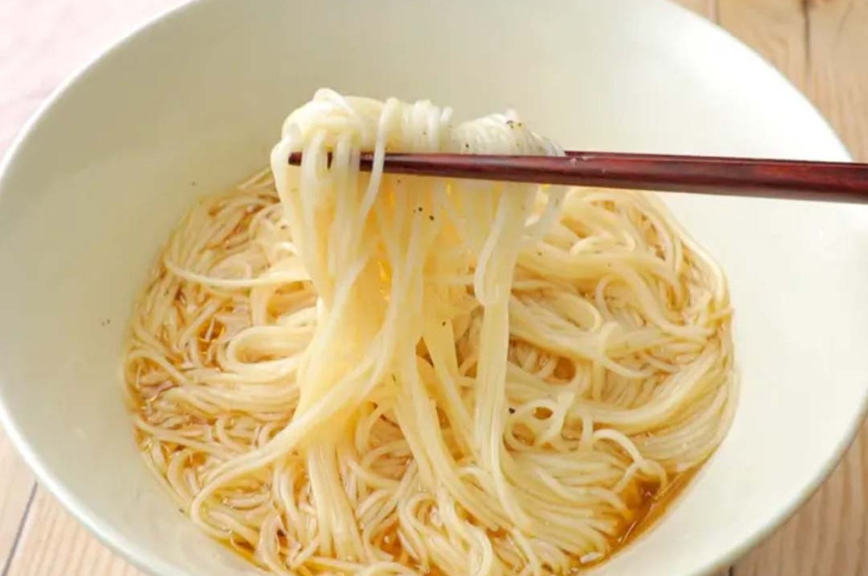 素麺が白い器に盛られ、箸で持ち上げられている。シンプルで美味しそうな一品。