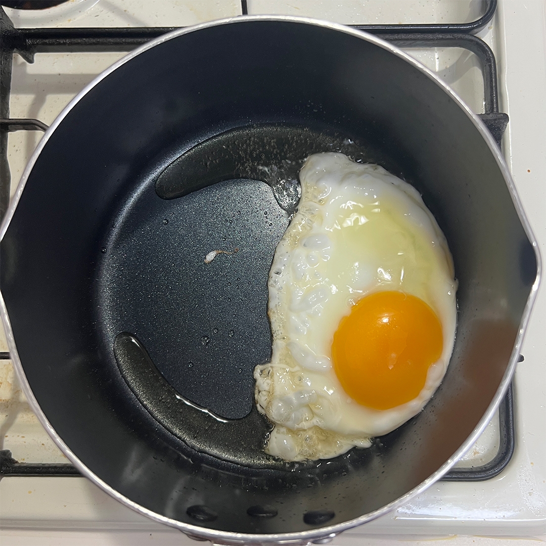 卵が片側だけ固まった状態でフライパンの中で調理されています。