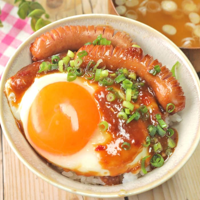 目玉焼きとウインナーがご飯の上にのった一品で、ネギが散りばめられた仕上げ。
