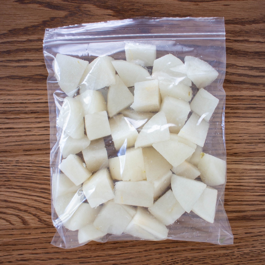 袋に入った一口サイズの白い果物または野菜の角切りがテーブルに置かれている。
