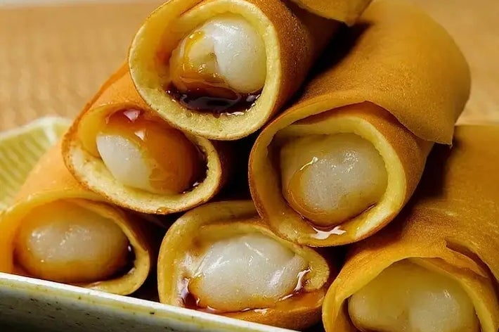 お皿に盛られたミルククリームが詰まった薄いクレープ巻き。香ばしい見た目が食欲をそそる。