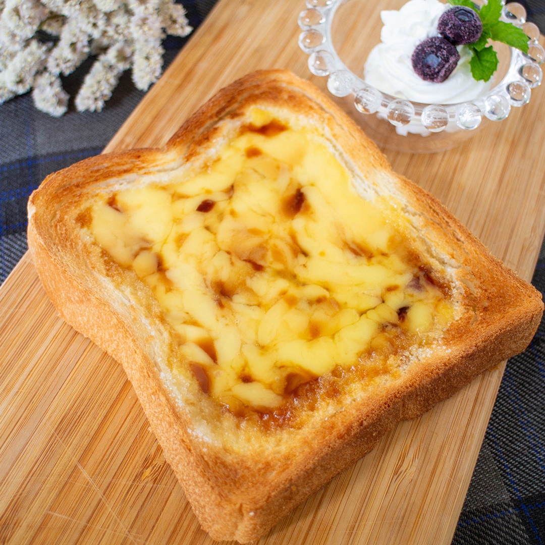 トーストに溶けたチーズ、横にホイップクリームと果物が添えられたデザートのイメージ。