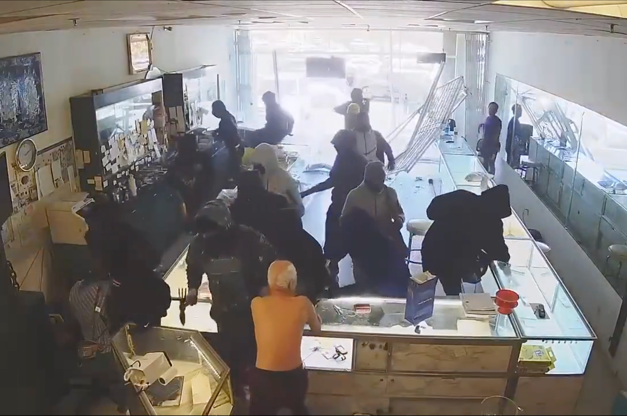 店内に複数人が押し寄せ、対面カウンター付近で騒動が起きている様子。ガラスが壊れている。