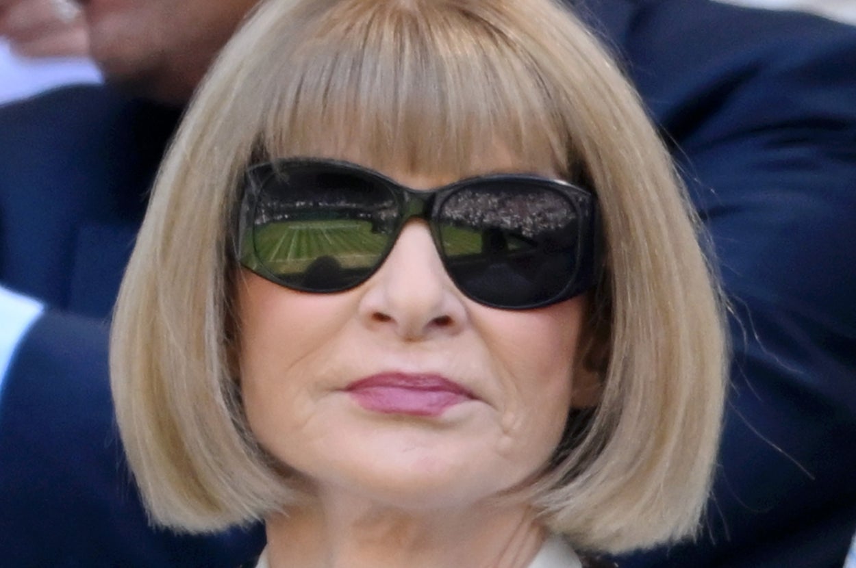 Person with bob haircut and sunglasses wearing a floral-patterned shirt and a colorful statement necklace