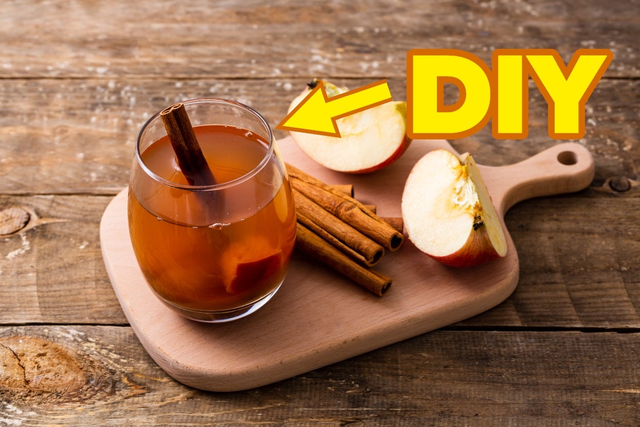 A glass of apple cider with cinnamon sticks on a wooden board, alongside apple slices. The word "DIY" is prominently displayed