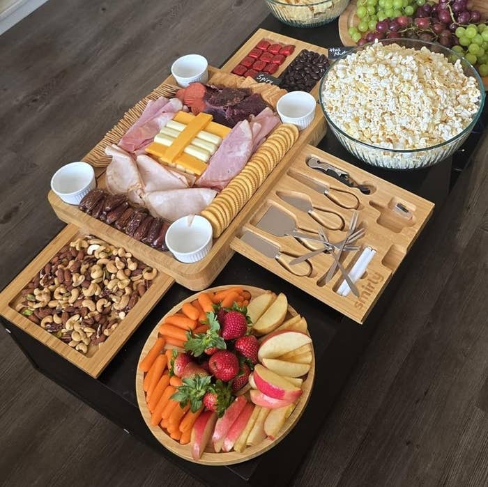 popcorn, grapes, assorted cheeses, meats, nuts, fruits, breadstuff rolls, and dips, acceptable for a gathering