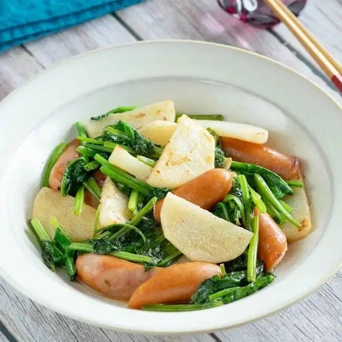 大根とソーセージ、青菜を使った炒め物が白い皿に盛られている。