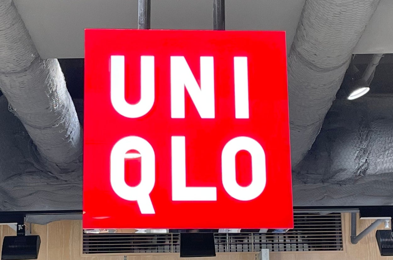 Bright red Uniqlo store sign hanging from the ceiling, with clothes displayed below