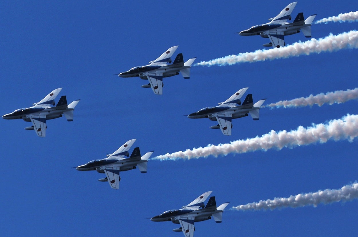 大阪・関西万博会場の上空を飛行する航空自衛隊の曲技飛行チーム「ブルーインパルス」=12日、大阪市此花区(時事通信社)