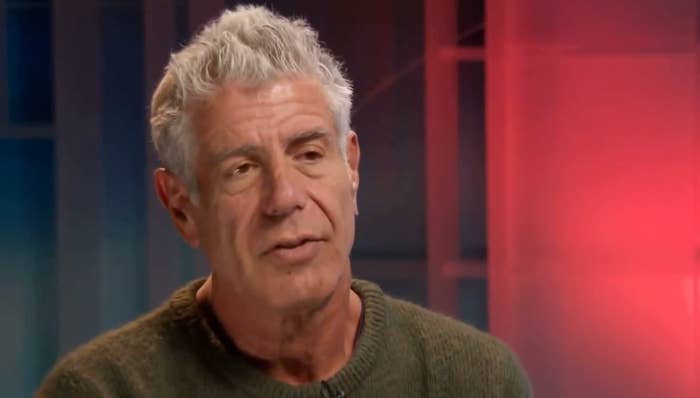 A person with short gray hair wears a casual sweater, sitting in an interview setting