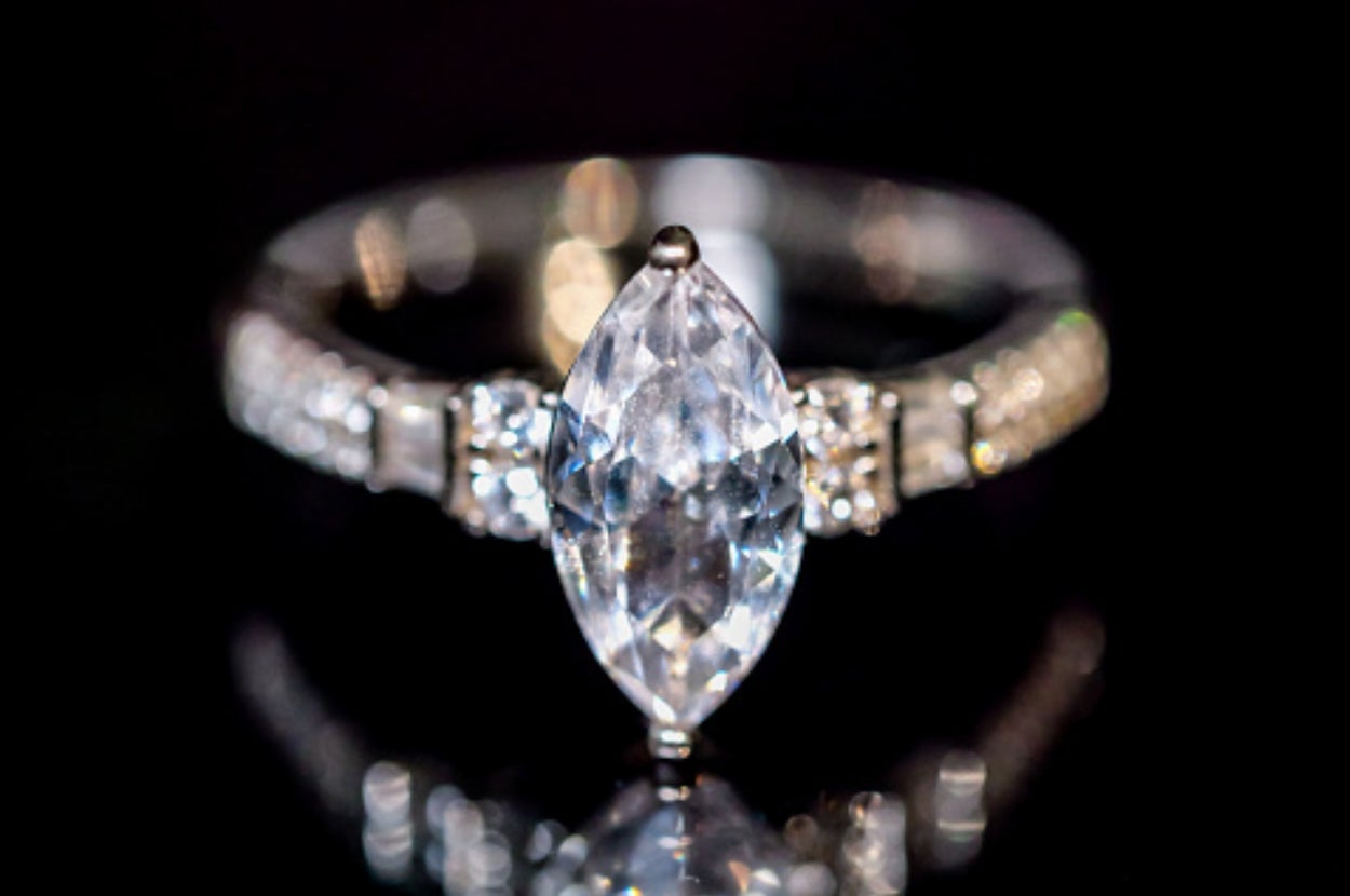 Marquise-cut diamond ring with side stones, shown against a black background, reflecting light for a sparkling effect