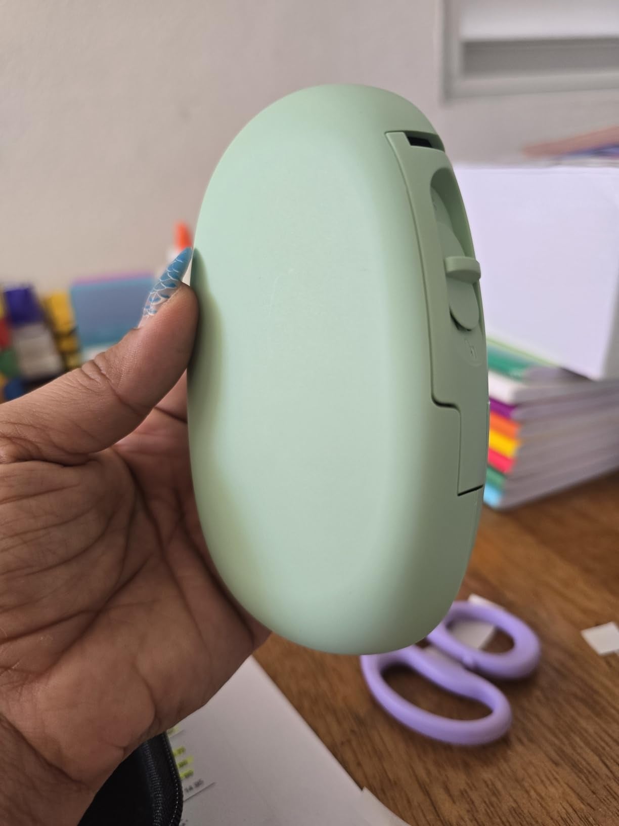 A person's manus  holds a sleek, oval-shaped gadget, perchance  for organizing oregon  idiosyncratic   care, with stationery items disposable   successful  the background