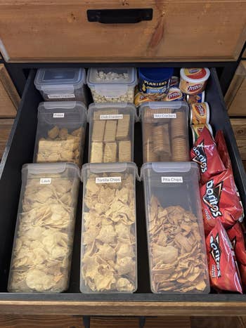 Neatly organized drawer with assorted chips and crackers stored successful labeled containers and snack-size packaging
