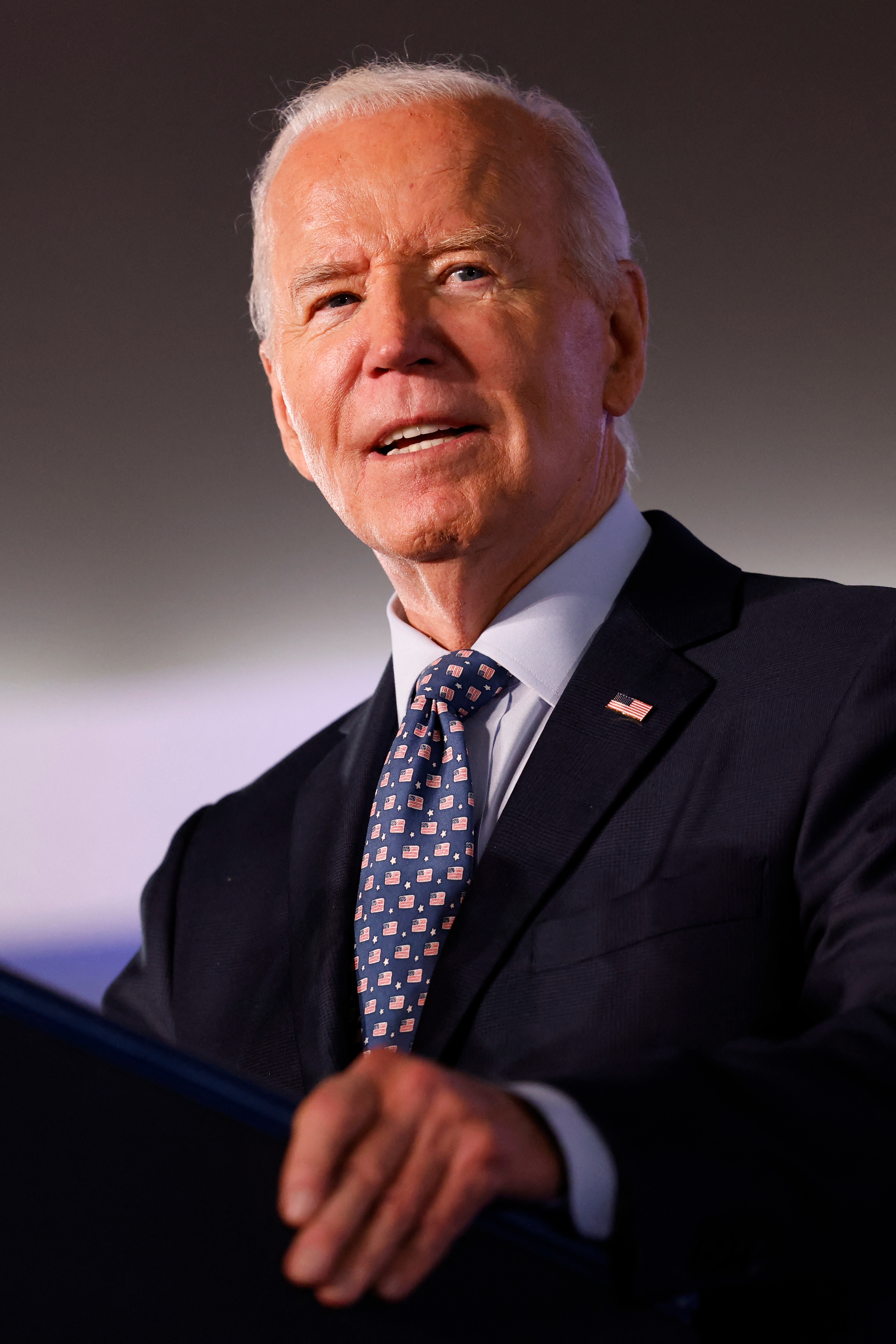Joe Biden in a suit and patterned tie speaks at a podium
